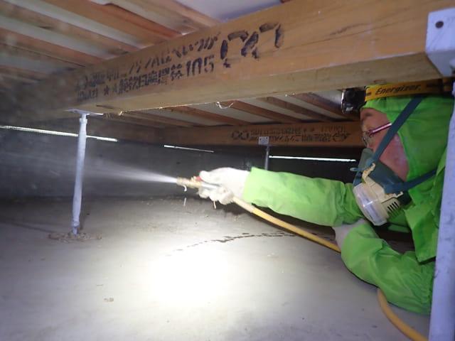 シロアリ駆除のため床下の土壌面全体に薬剤を散布する作業の様子